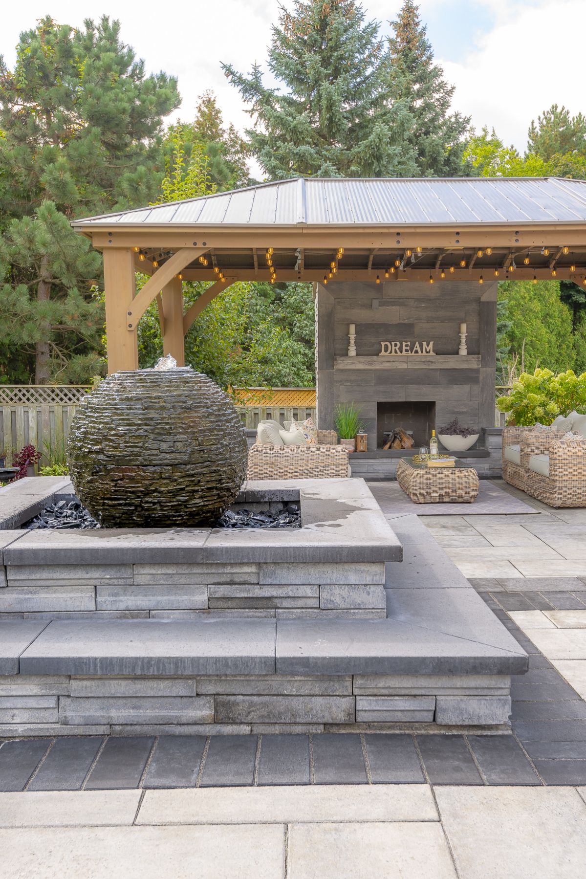 A beautifully landscaped patio in Kleinburg featuring a fire pit and water fountain.
