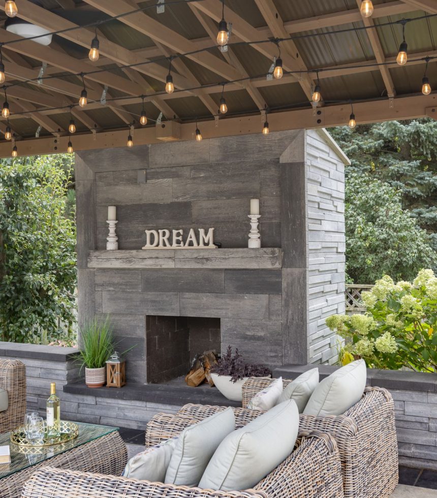 An outdoor living area with wicker furniture and a fireplace.