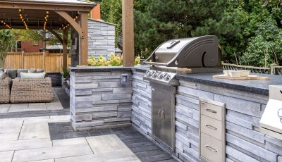 An outdoor kitchen with a grill and patio furniture.